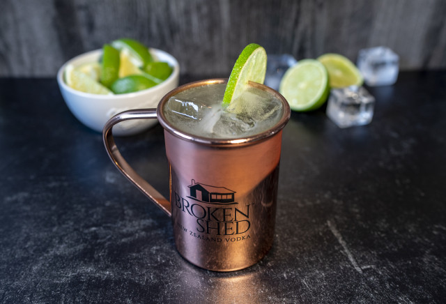 A Broken Mule cocktail in a copper mug with limes